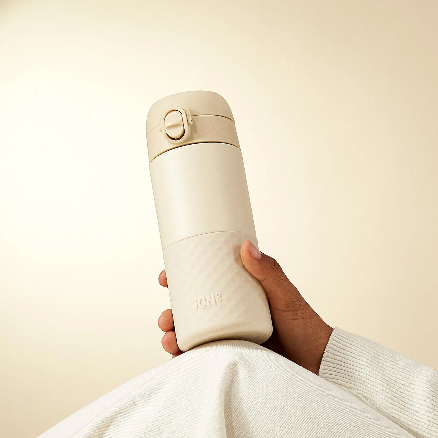 the new ion8 travel mug shown on top of a knee in tuberose