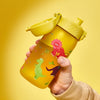 A yellow plastic sippy cup, decorated with dinosaur silhouettes, is being held against a solid yellow background.