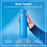 A blue, stainless steel water bottle is being held. Its flip top opens one-handed. The background is light blue. 