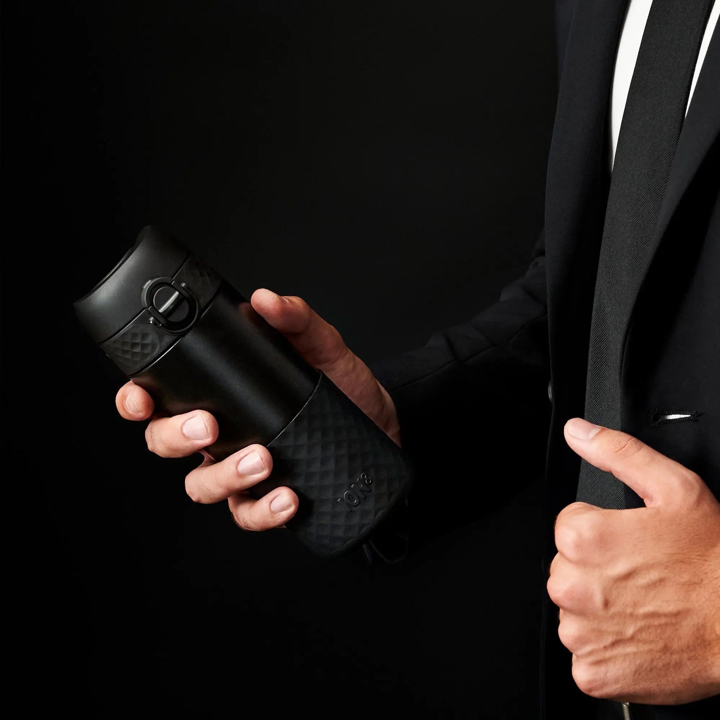 man dressed in black tuxedo holding black ION8 hotshot travel mugs