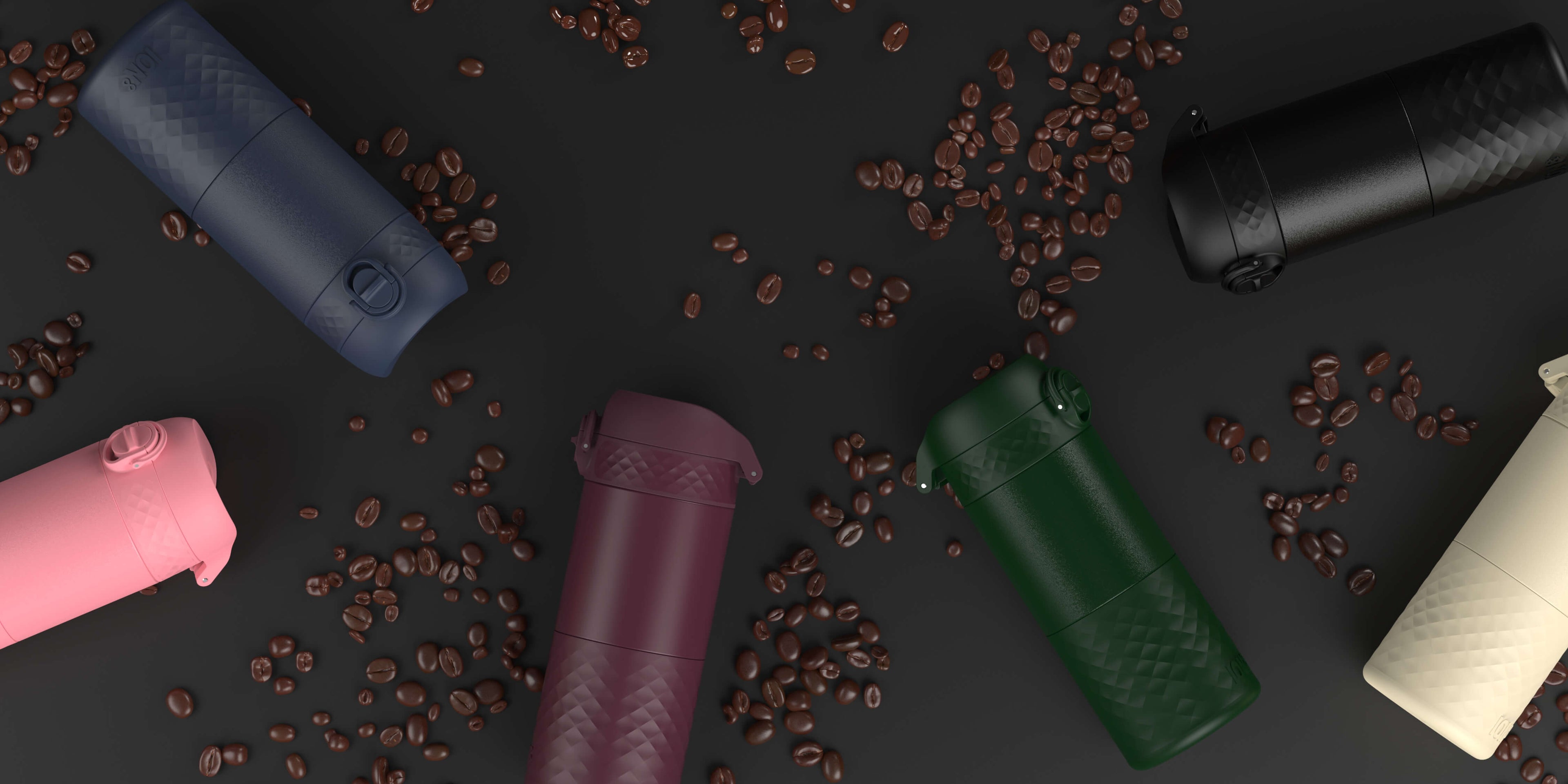 Several portable coffee makers, in various colors, are scattered on a dark surface amongst coffee beans.