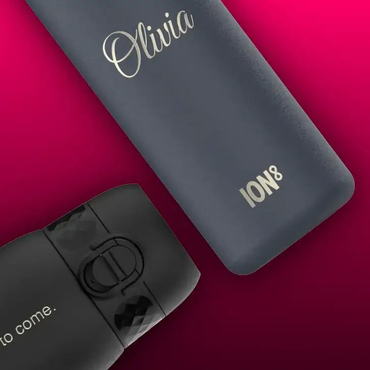 Two water bottles rest on a crimson background. One dark grey bottle is personalized “Olivia” and branded “ION8”. The other black bottle displays “to come.”