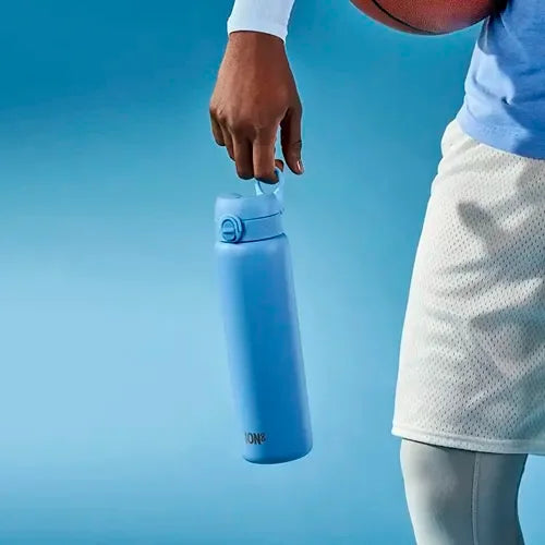 A person holds a blue ION8 water bottle; they are also holding a basketball against their side, wearing athletic clothing against a blue background.
